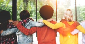 Three people with arms around top of shoulders with backs facing